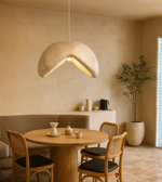 Handcrafted earthen pendant light with organic curved design over wooden table