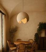 Sculpted globe pendant light illuminating a minimalist natural dining area