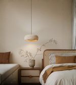 Minimal zen stone pendant light illuminating a natural bedroom interior.