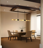Long marble-effect linear chandelier hanging above elegant beige dining table setup.