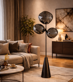 Modern smoked glass cluster floor lamp with black stand placed beside sofa in contemporary living room