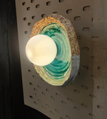 Ceramic wall sconce with a light bulb on a pegboard background