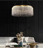 Modern crystal chandelier over elegant living room with gold tables and plush sofa