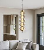 Modern gold pendant light with glass accents hanging above a neutral living room sofa