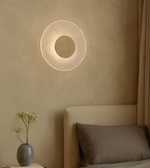 Round stone halo wall light creating warm ambient glow above bedside table