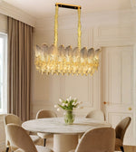 Leaf etched glass dining chandelier with warm lighting above a marble dining table in a luxury interior