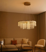 Sereno Curve chandelier with layered golden glass ribbons lighting up warm beige lounge.