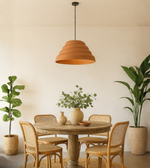 Terracotta dome pendant light hanging above rustic round dining table with plants