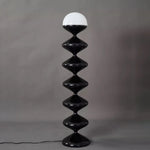 Close-up of glossy black geometric floor lamp with dome diffuser