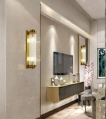 Modern living room with gold wall sconces, TV, and decorative elements.