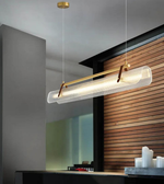 Modern pendant light fixture hanging in a room with wooden wall and glass panel.