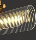 Close-up of a ribbed glass pendant light with gold fixture on a dark background