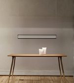 Modern pendant light fixture hanging above a wooden table with decorative items.