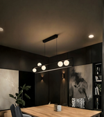 Modern interior with a long linear pendant light fixture in a darkly decorated room.