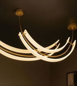Modern chandelier with curved arms on a dark ceiling