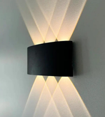 Modern wall-mounted light fixture casting geometric shadows on a gray wall.