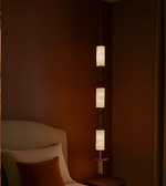 Pendant light fixture with three lampshades in a dimly lit room.