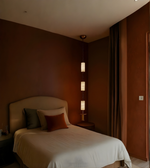 Bedroom with a bed and lamp against a brown wall