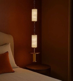 Modern pendant light fixture on a bedside table against a warm-toned wall.