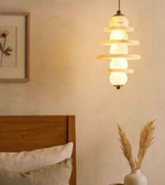 Decorative pendant light hanging above a bed in a bedroom setting.