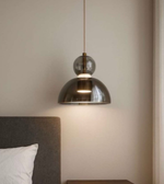 Modern pendant light hanging above a bed in a bedroom setting