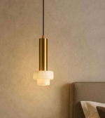 Gold pendant light fixture on a neutral wall with a soft glow