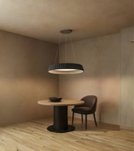 Modern dining area with a round table and chair under a pendant light in a softly lit room.