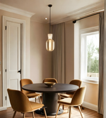 Dining room with round black table and four brown chairs near a window.