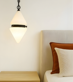 Pendant light fixture above a bed with pillows in a bedroom setting