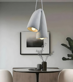 Modern pendant light fixture on a neutral wall with pillows in the foreground