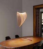 Modern pendant light hanging above a wooden table in a room with a door in the background.