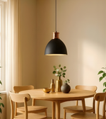 Dining room with a round wooden table and chairs, featuring a black pendant light and decorative vases.