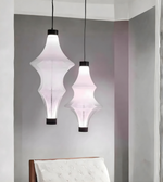 Two pendant lights hanging from the ceiling in a room with a bed in the foreground.