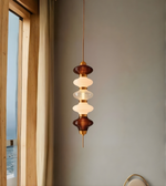 Modern pendant light hanging in a room with a window and neutral wall.