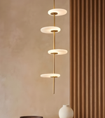 Modern pendant light fixture against a beige wall with a brown curtain.