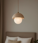 Wooden pendant light hanging above a bed with neutral bedding.