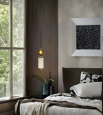 Modern bedroom with a bed, decorative pillow, framed artwork, and pendant light.