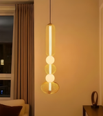 Modern pendant light hanging in a room with a window and curtain.