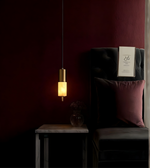 Dark room with a chair, lamp, and decorative item against a red wall.