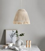 Beige pleated pendant lamp hanging above a table with decorative items.