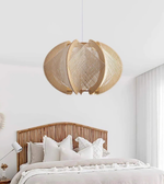 Woven pendant light fixture above a bed in a bedroom setting