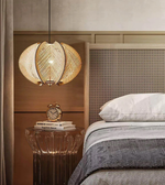 Woven pendant light fixture above a bed in a bedroom setting