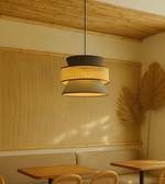 Modern pendant light fixture in a cozy room with wooden tables and a bamboo wall.