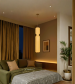 Modern bedroom with a green sofa, pendant light, and framed picture.