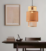 Woven pendant light hanging above a wooden table with a framed picture on the wall.