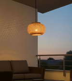 Woven pendant light hanging above a sofa on a balcony at dusk.