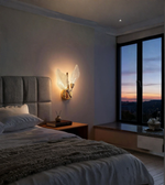 Elegant leaf-inspired wall lamp used as a bedside light in a modern bedroom