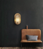 Decorative gold wall light illuminating a dark accent wall with warm glow