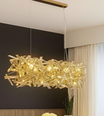 Modern gold chandelier hanging in a room with a dark wall and window.