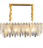 Chandelier with gold frame and feather-like glass elements on a white background